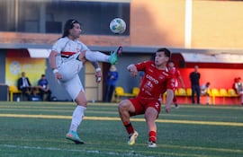 Diego Máximo "Chino" Martínez (izquierda), goleador del Atlético Tembetary, levanta la pierna intentando conectar el balón ante el marcador de punta Alfredo Duarte.