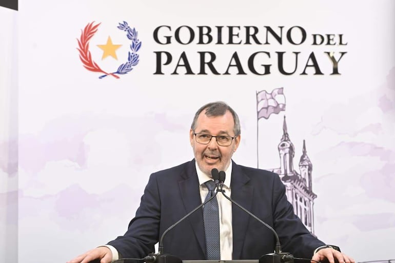 Carlos Carvallo en traje oscuro y gafas, habla en podio marcado con 'GOBIERNO DEL PARAGUAY'.
