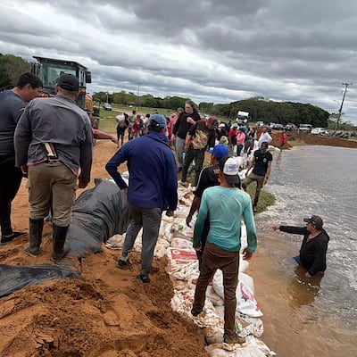 Pobladores de Paso de Patria trabajan contra reloj cargando bolsas de arena para evitar que el agua corte el camino e ingrese al casco urbano.