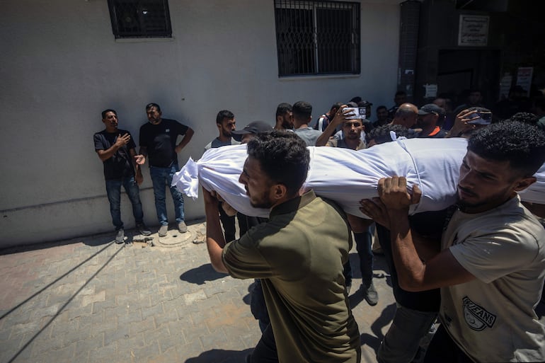 Palestinos trasladan el cuerpo de una víctima al hospital Al-Shifa en Ciudad de Gaza, el 14 de julio de 2026. Al menos siete palestinos murieron en un ataque israelí contra una comisaría de policía en Jabalia, en el norte de Gaza, según el Ministerio de Salud de Gaza.