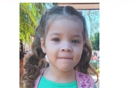Niña de 5 años con cabello rizado y camiseta verde, en un entorno exterior con texto 'SE BUSCA' en rojo.