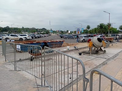 Área de construcción en el aeropuerto con mezcladora de cemento y barreras de seguridad, bajo un cielo nublado.