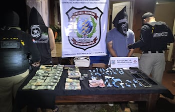 Adolfo Ezequiel Espínola González y Mathias José González junto con las evidencias encontradas en poder de ambos durante un allanamiento en Guarambaré, bajo el resguardo de los agentes antidrogas de la Policía.