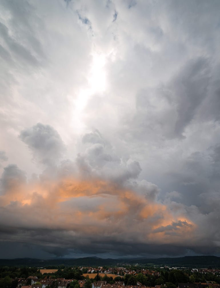 Paisaje rural paraguayo bajo nubes grises y un resplandor anaranjado, indicando tormenta inminente.