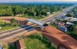 Vista aérea de un viaducto en construcción sobre una carretera rural, sin personas visibles alrededor.