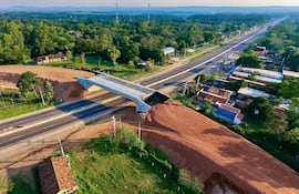 Vista aérea de un viaducto en construcción sobre una carretera rural, sin personas visibles alrededor.