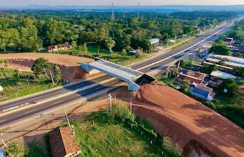 Vista aérea de un viaducto en construcción sobre una carretera rural, sin personas visibles alrededor.