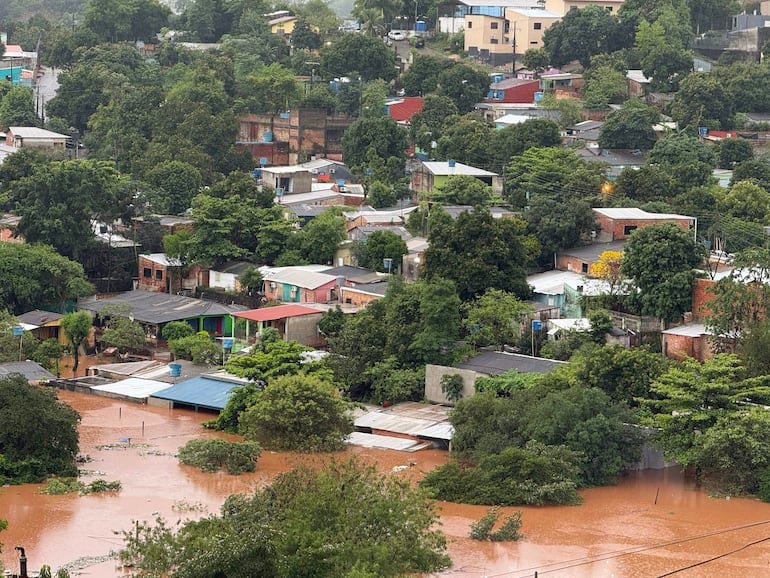 Zona inundada en barrio Dan Rafael, con casas parcialmente sumergidas y árboles rodeando el área.