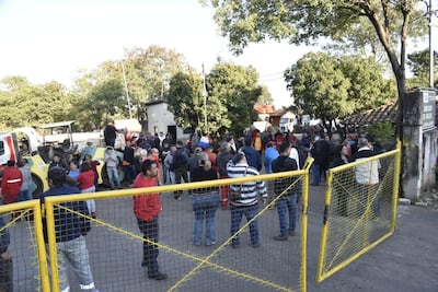 Grupo de personas en chaquetas y camisetas rojas reunidas al aire libre, conversando en un ambiente de protesta.
