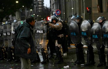 Un policía antidisturbios apunta con una escopeta durante una protesta frente al Congreso Nacional en Buenos Aires el 6 de agosto de 2026, mientras los senadores debaten un proyecto de ley sobre la inviolabilidad de la propiedad privada.