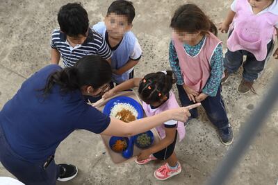Niños reciben el almuerzo en el patio de una escuela, en Asunción.