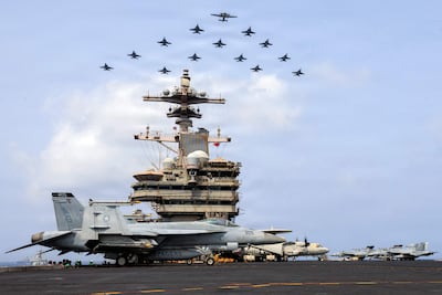 Aviones militares estadounidenses volando en formación sobre el portaaviones George H.W. Bush en el mar Arábigo.
