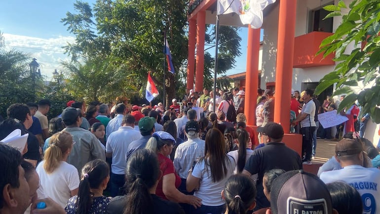 Multitud con banderas y carteles en apoyo al intendente Agustín Ovando frente a un edificio gubernamental.