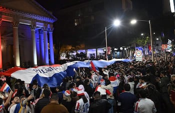 Gran celebración con bandera paraguaya y personas en camisetas nacionales, visiblemente emocionadas en la calle Palma.