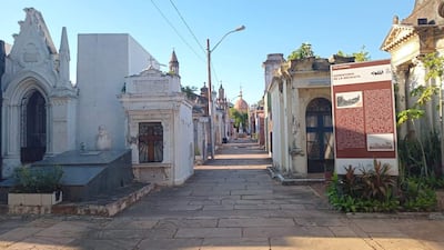 Cementerio de la Recoleta con tumbas elaboradas, camino empedrado y cúpula al fondo bajo un cielo despejado.