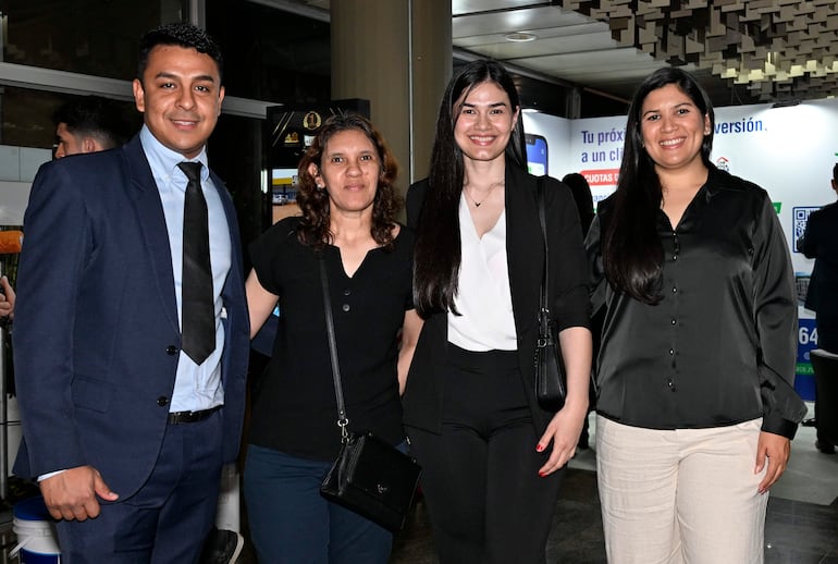 Cuatro mujeres y un hombre sonríen en un ambiente bien iluminado, vistiendo trajes elegantes, en la Gran Gala de la construcción.