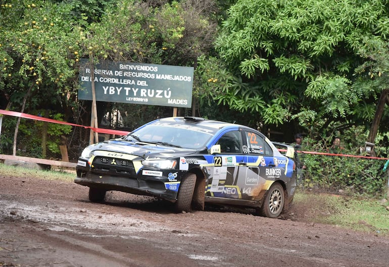 Vehículo Mitsubishi número 22 en movimiento sobre terreno fangoso, con vegetación densa en el fondo.