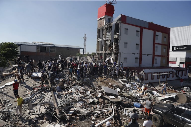 Personas caminan sobre los escombros de un edificio colapsado este lunes, en Cali (Colombia). Al menos 20 edificios sufrieron graves daños por consecuencia del terremoto de magnitud 7,4 que sacudió la mayor parte del país, con epicentro en la zona del Pacífico.