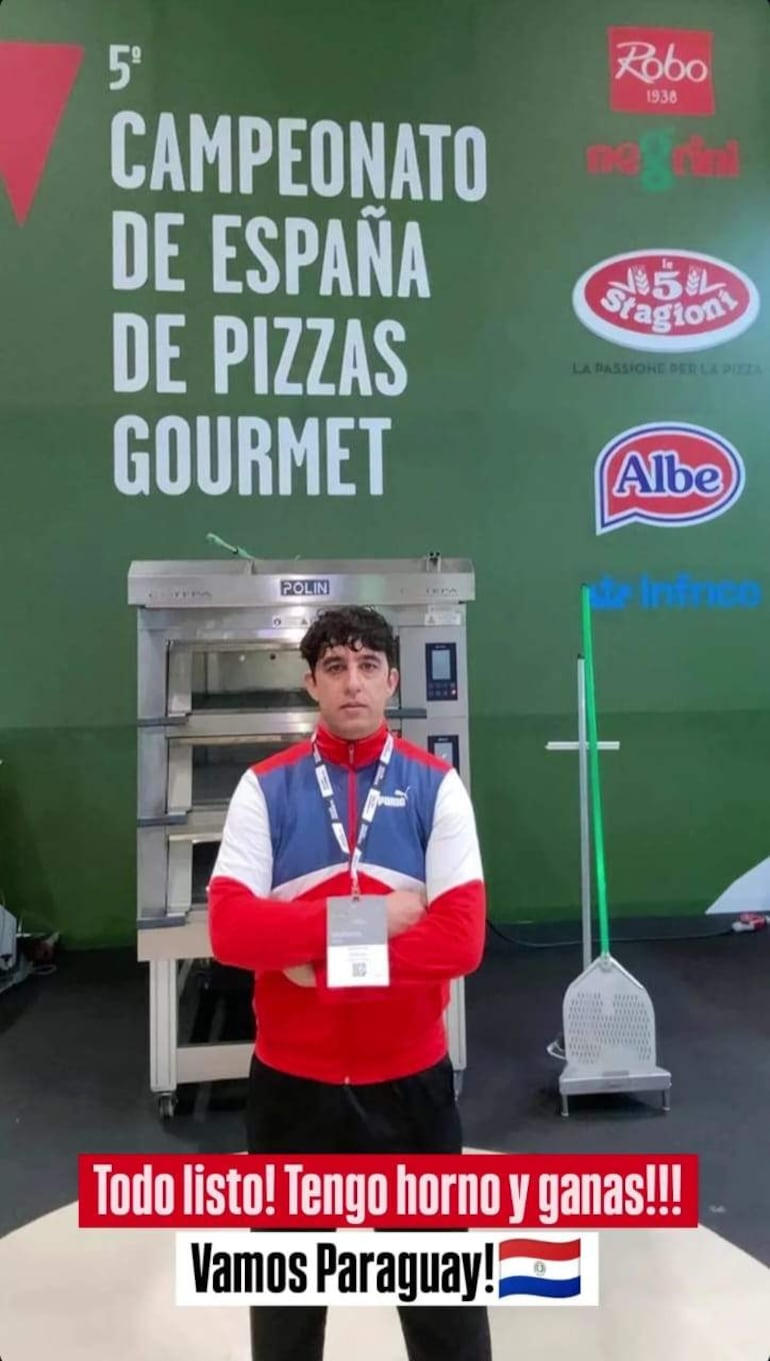 Martín Dumm en chaqueta roja y blanca, sonríe junto a un horno de pizzas, sosteniendo un cartel de apoyo a Paraguay.