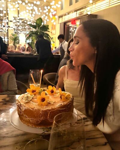 Meghan Markle a punto de apagar las velitas de su torta el día de su cumpleaños número 44.