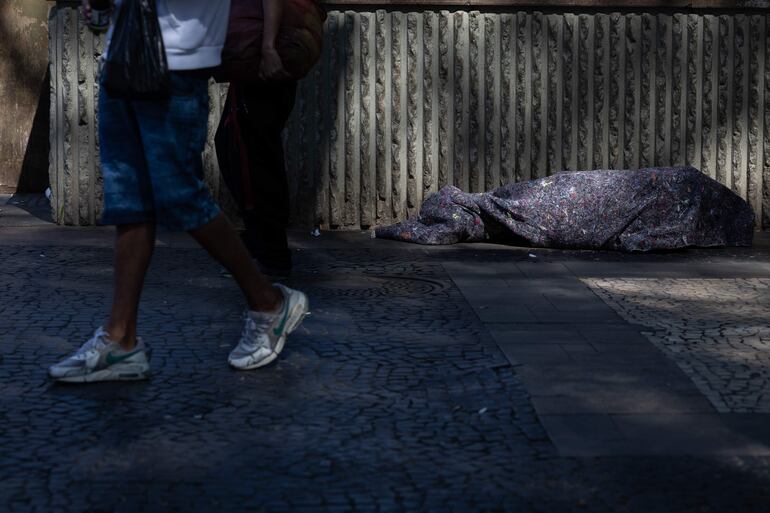 Un habitante de calle duerme en la plaza de la Sé, donde se encuentra la Catedral Metropolitana, en Sao Paulo (Brasil).