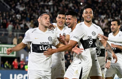 Futbolistas de Olimpia en camiseta blanca celebran un gol con gestos de alegría en el estadio Defensores del Chaco.