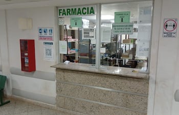 Área de farmacia sin personas, mostrador con instrucciones de seguridad y horario de atención señalado.