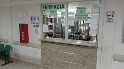Área de farmacia sin personas, mostrador con instrucciones de seguridad y horario de atención señalado.