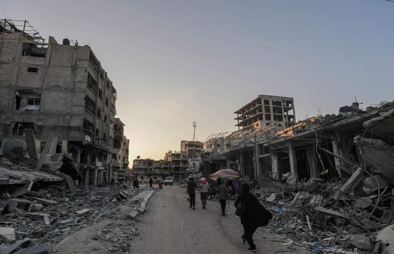 Palestinos desplazados recorren una calle llena de escombros en Jan Yunis, el domingo.