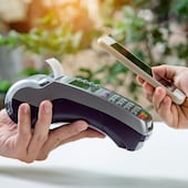 Una persona realiza un pago en un pos, con un código QR, utilizando su smartphone.
