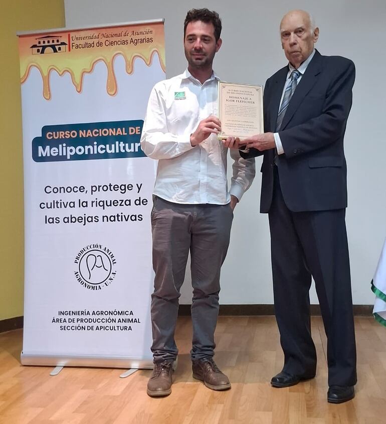 El Ing. Ever Rodríguez, director del departamento de meliponicultura de la Facultad de Ciencias Agrarias de la UNA entrega la distinción a Igor Fleischer.