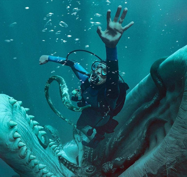 Buzo con equipo de inmersión bajo el agua, levantando una mano mientras un pulpo lo envuelve con sus tentáculos.