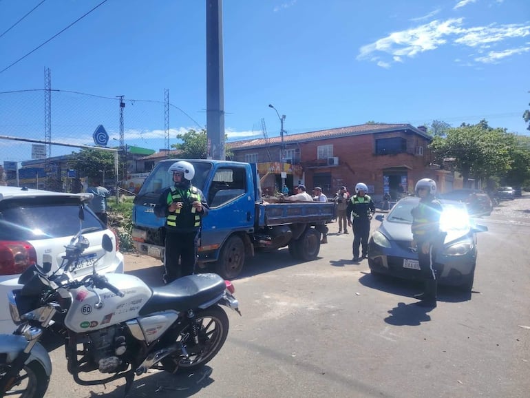 Cuatro policías uniformados en motocicletas y chaquetas reflectantes, supervisando una calle urbana junto a un camión.