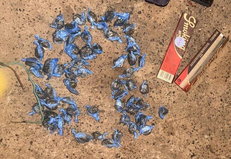 Superficie de concreto con paquetes de papel de fumar y envoltorios en colores azul y negro, sin personas presentes.