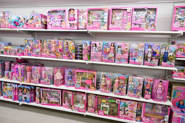 Exhibición de muñecas Barbie en estanterías, con cajas coloridas en rosa y morado, sin personas visibles.