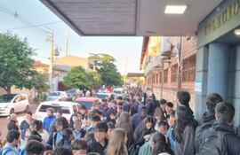 Multitud de estudiantes frente al colegio Villa San Francisco, vestidos informalmente, algunos con mochilas y chaquetas, conversando y usando teléfonos móviles.