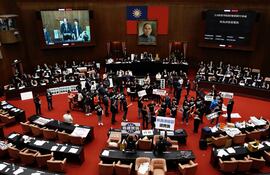 Legisladores del partido Kuomintang (KMT) de Taiwán sostienen pancartas dentro del parlamento.
