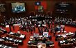 Legisladores del partido Kuomintang (KMT) de Taiwán sostienen pancartas dentro del parlamento.
