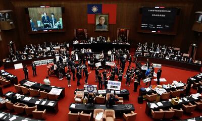 Legisladores del partido Kuomintang (KMT) de Taiwán sostienen pancartas  dentro del parlamento.