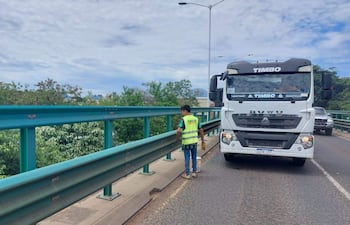 Trabajador con chaleco reflectante verde en el viaducto de Madame Lynch, mientras un camión TIMBO pasa por su lado.