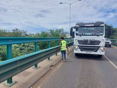 Trabajador con chaleco reflectante verde en el viaducto de Madame Lynch, mientras un camión TIMBO pasa por su lado.
