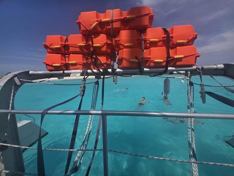 Faro gris con detalles rojos rodeado de un paisaje árido y cielo nublado, sin personas visibles
