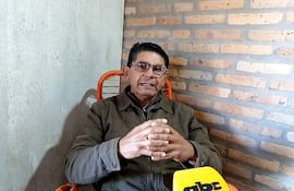 Roberto Ayal, hombre canoso con gafas y chaqueta gris, enfatiza su discurso sentado ante un micrófono en una habitación sencilla.