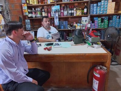 Gonzalo Melgarejo (c) y un allegado miran el lugar donde impactó uno de los disparos en la mesa.