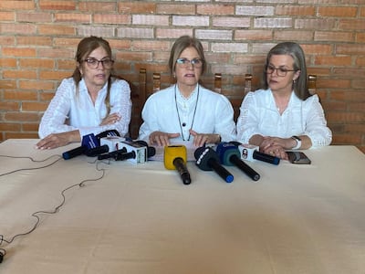 Beatriz y Lorena Denis Bareiro, con camisas blancas, escuchan y hablan en conferencia, rodeadas de micrófonos en un ambiente informal.