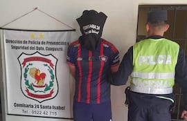 Individuo con capucha negra y camiseta roja y azul es detenido por agentes de la policía en comisaría.