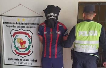 Individuo con capucha negra y camiseta roja y azul es detenido por agentes de la policía en comisaría.