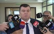 Dionisio Amarilla, con corbata, rodeado de periodistas con micrófonos en un ambiente formal.