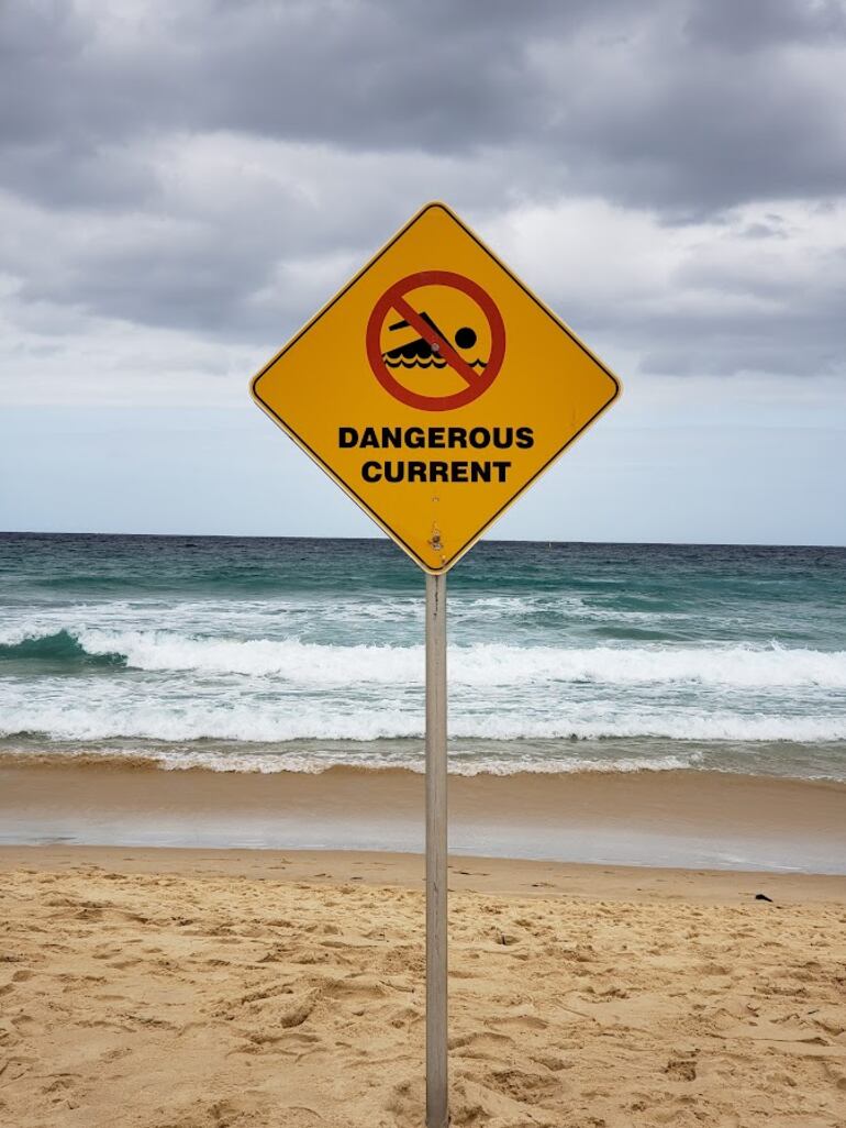 Un cartel señala la presencia de una corriente de agua peligrosa en el mar, frente a la playa de Bondi, en Sídney, Australia.