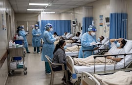 Cuatro médicos con equipo de protección atienden a pacientes en camillas, en un ambiente hospitalario crítico sobre la influenza.